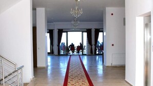 A spacious hotel lobby with a red carpet, a chandelier, and large windows. - Hasdikoz Abdik Hotel (Of)