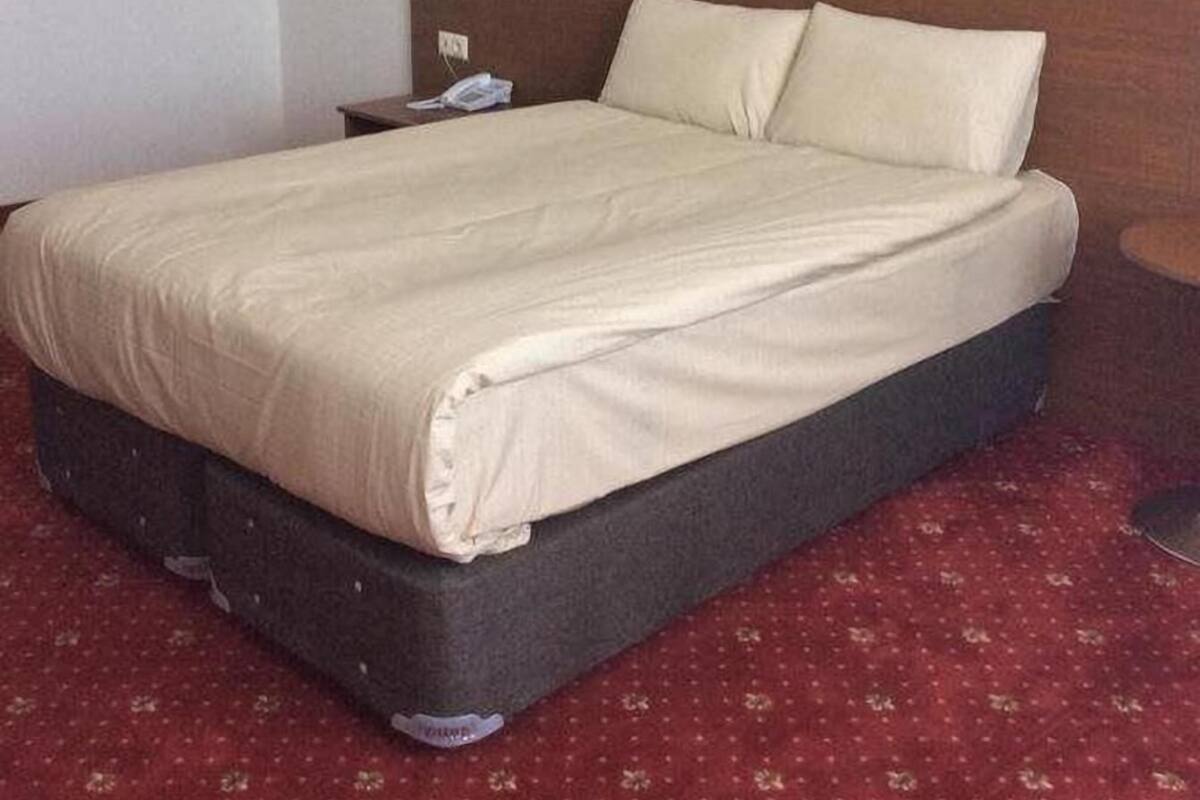 A hotel room with a bed, a nightstand, and a telephone.