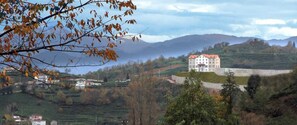 A large building with a red roof, surrounded by terraced fields and hills in the background. - Hasdikoz Abdik Hotel (Of)