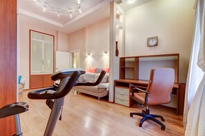 Relax in this well-appointed room featuring a treadmill, sofa, desk, and large window.