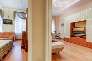 Relax in this stylish living room with a large flat-screen TV, comfortable sofa, and home fitness area featuring a treadmill and stationary bike.