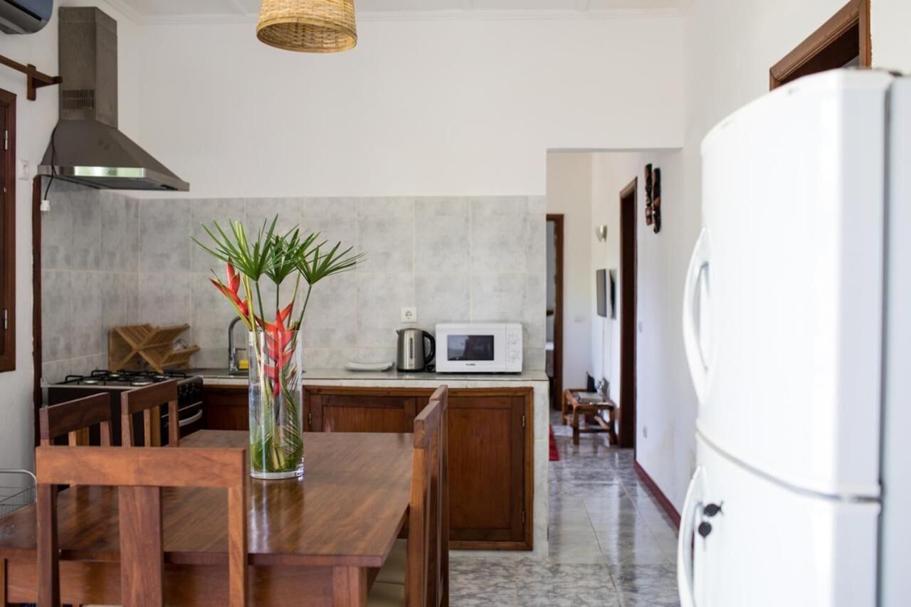 Cozinha com mesa de jantar, micro-ondas e geladeira.