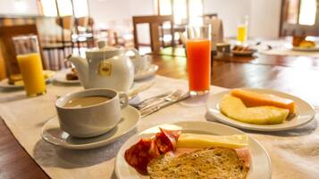 Une table mise pour le petit-déjeuner, avec une nappe pour deux personnes, comprenant des assiettes avec des toasts, des œufs, du bacon et une tasse de café.