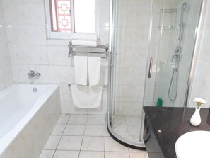 A modern bathroom with a bathtub, a glass-enclosed shower, and a vanity with a vase. - Sogecoa Apart Hotel (Maputo)