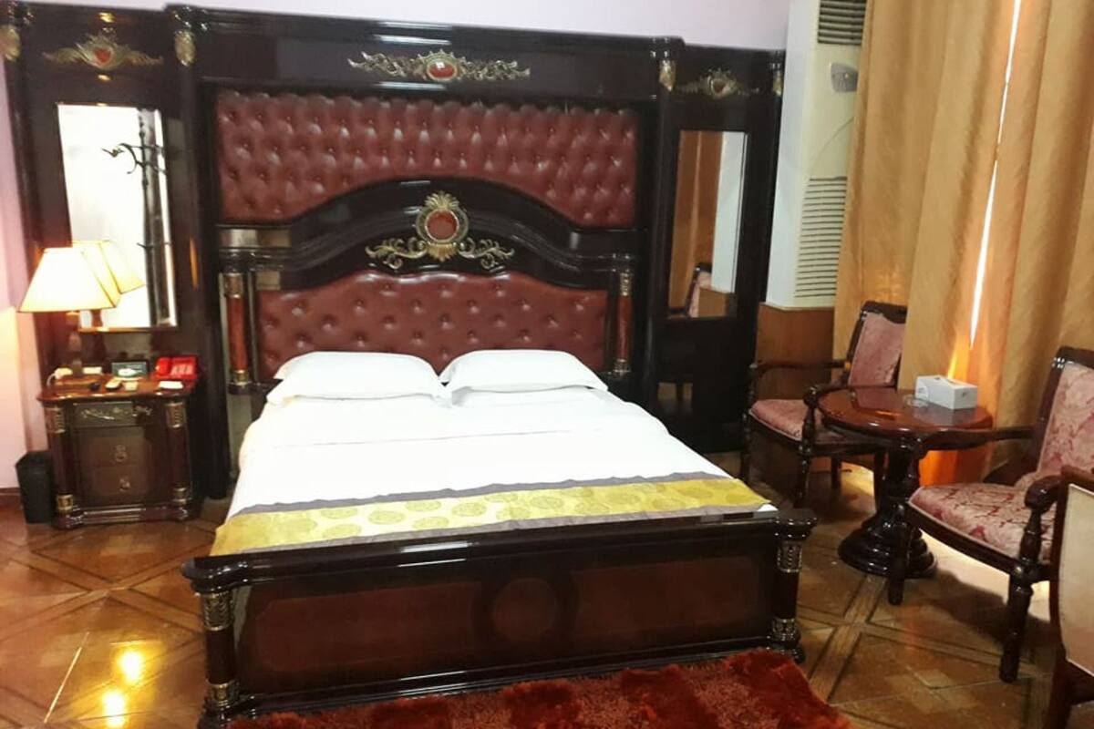 Une chambre d’hôtel avec un grand lit, une table de chevet, une chaise et un miroir.