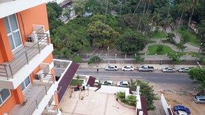 A multi-story building with a tiled rooftop patio area, surrounded by greenery and parked cars. - Sogecoa Apart Hotel (Maputo)