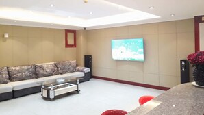 A modern living room with a sofa, a coffee table, a TV mounted on the wall, and red chairs. - Sogecoa Apart Hotel (Maputo)