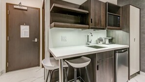 Una cocina compacta con encimera blanca, electrodomésticos de acero inoxidable y armarios de madera.