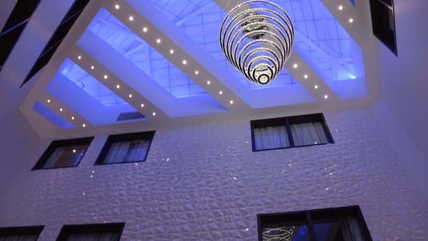 Un interior moderno con un diseño geométrico en el techo, tragaluces y una lámpara central.