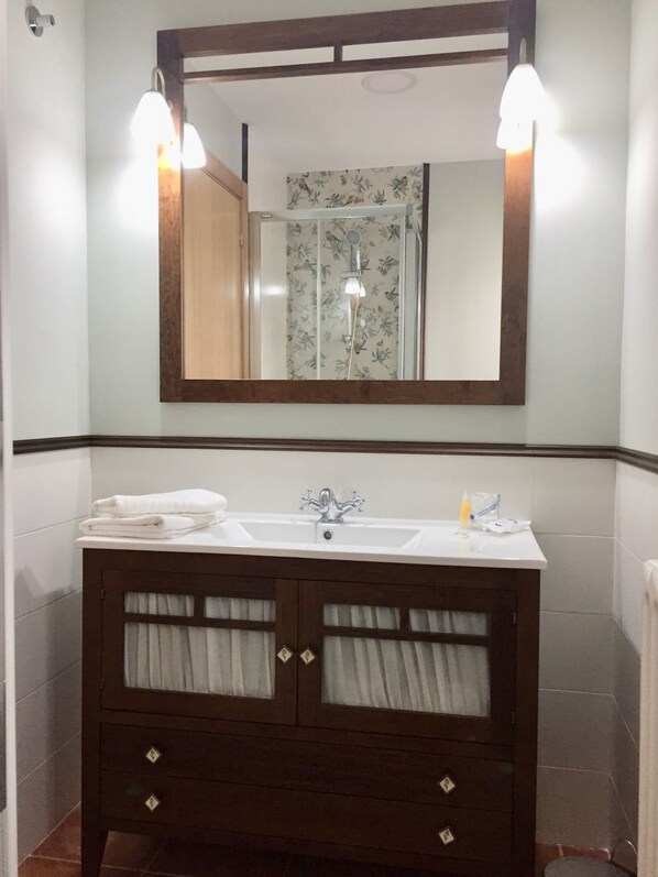 A bathroom with a dark wooden vanity, two sinks, and a large mirror with lights.