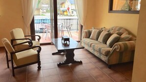 Una sala de estar con un sofá, dos sillones, una mesa de centro y vistas al exterior.
