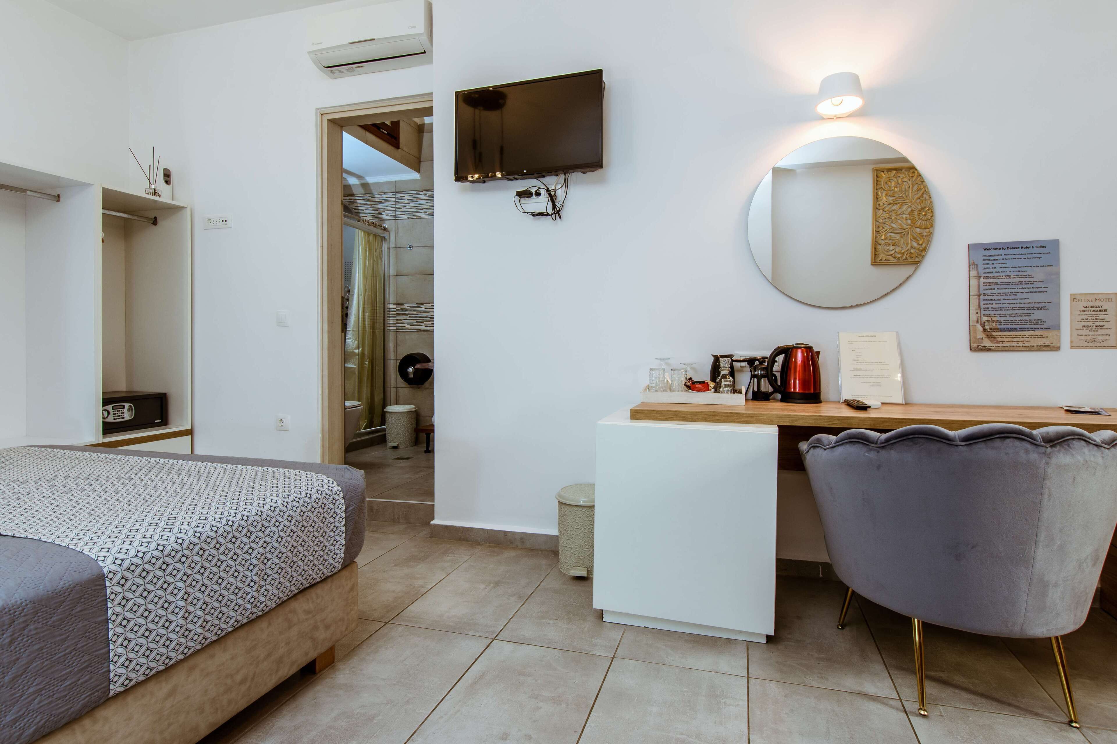 A modern hotel room with a bed, a desk with a chair, a television, and a mirror.