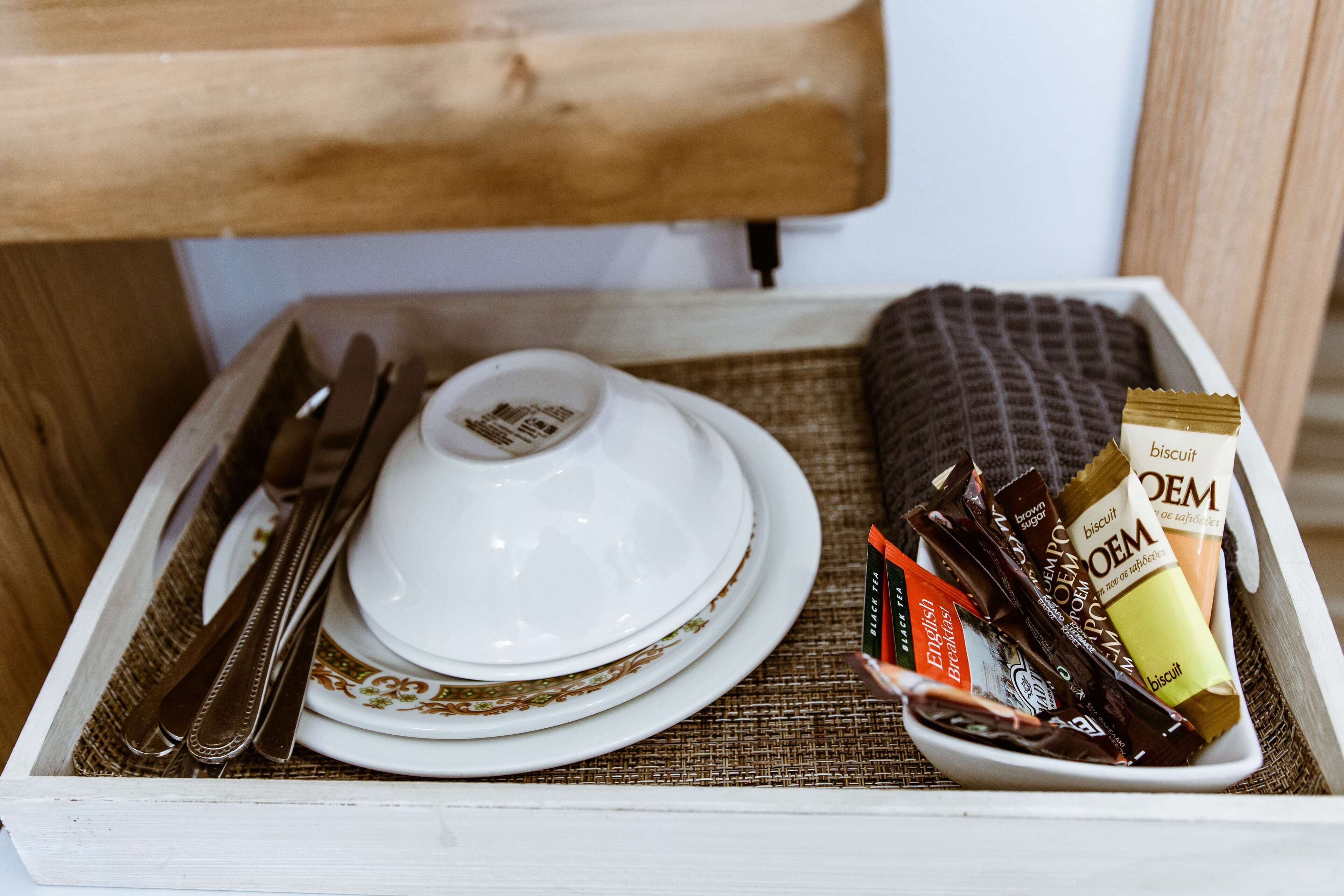A tray with a white plate, a bowl, a knife, a spoon, and a box of biscuits.
