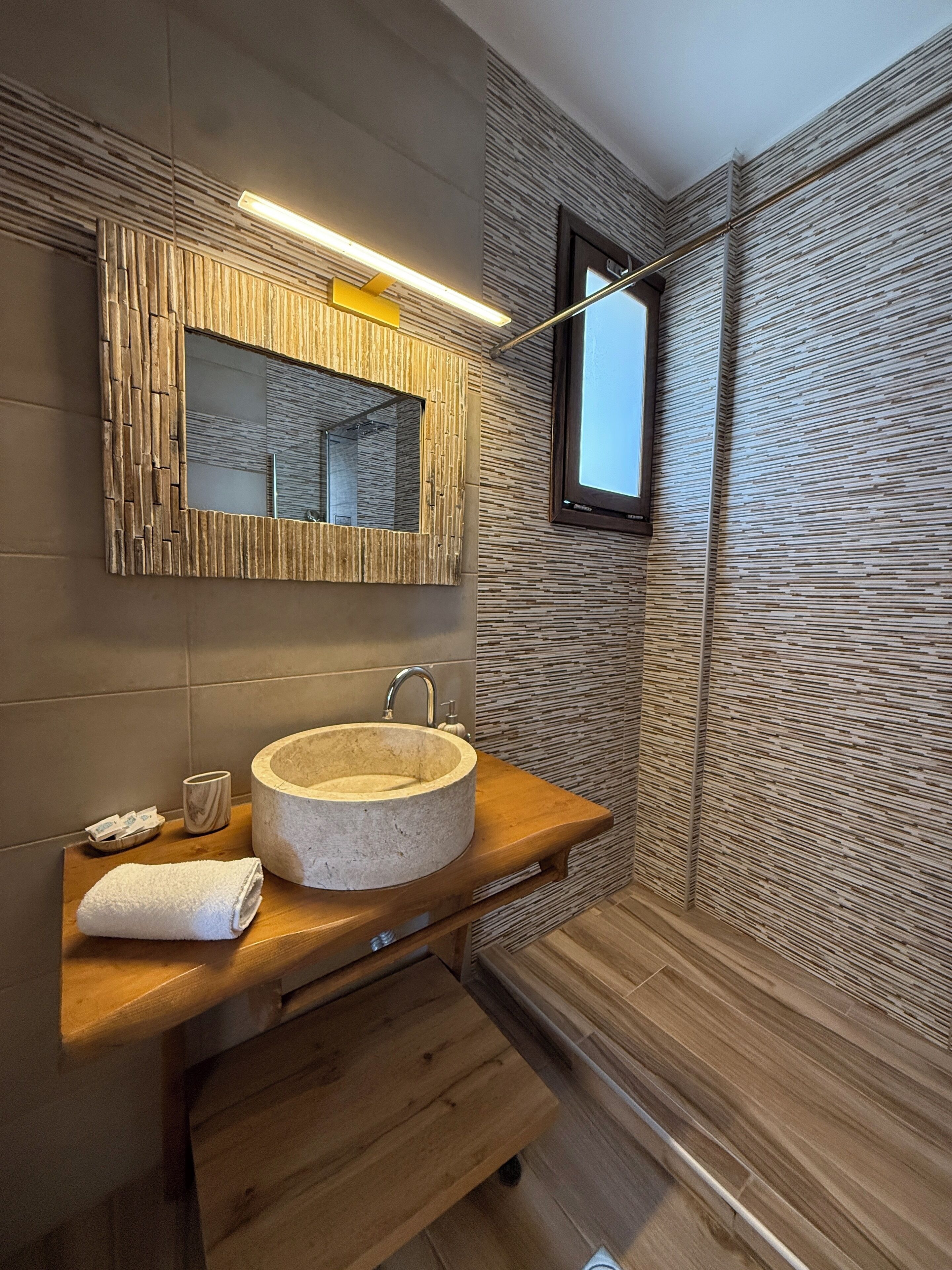 A modern bathroom with a stone sink, wooden vanity, and a textured wall design.