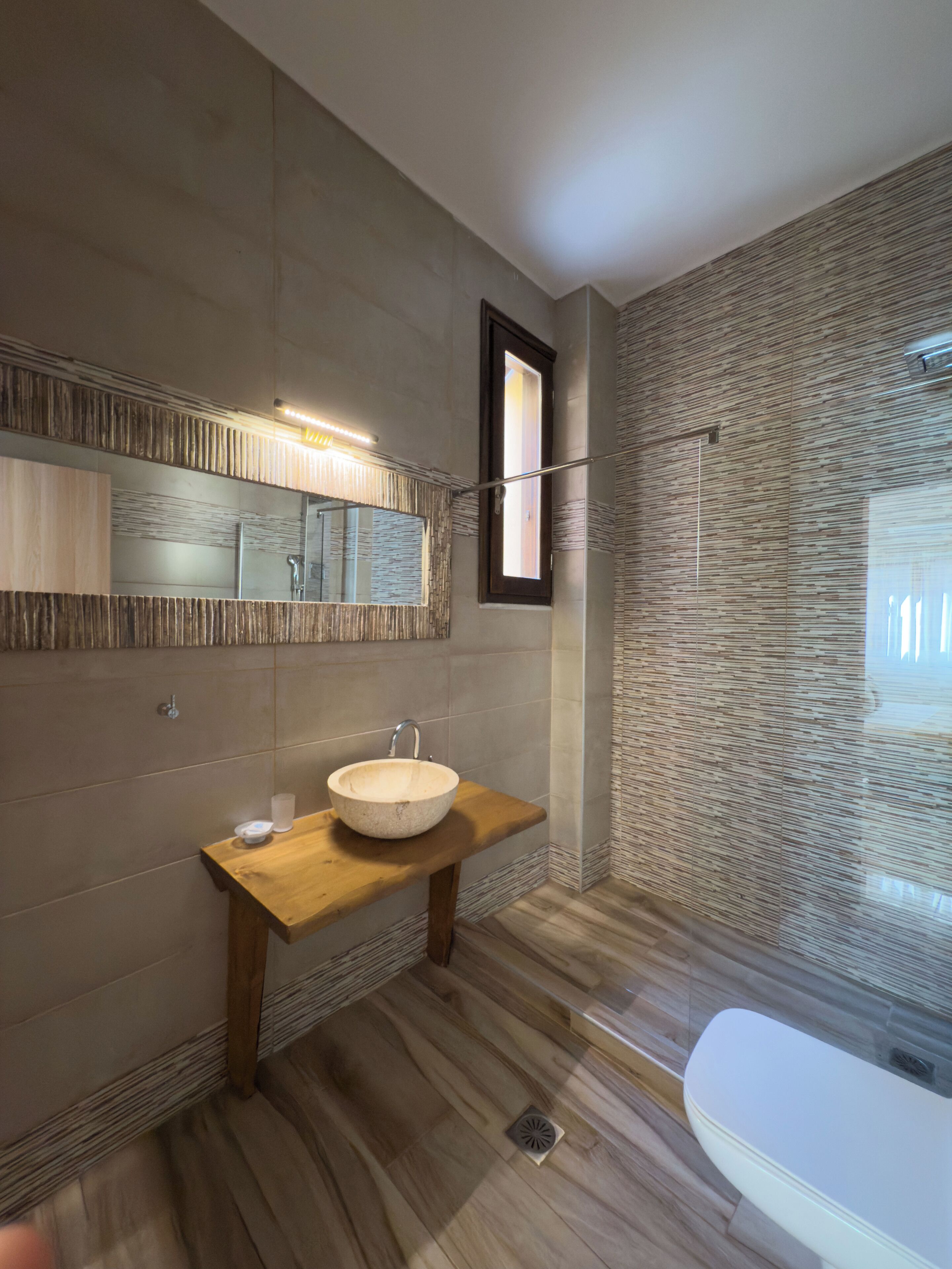 Une salle de bain moderne avec un meuble-lavabo en bois, un grand miroir et une baignoire.