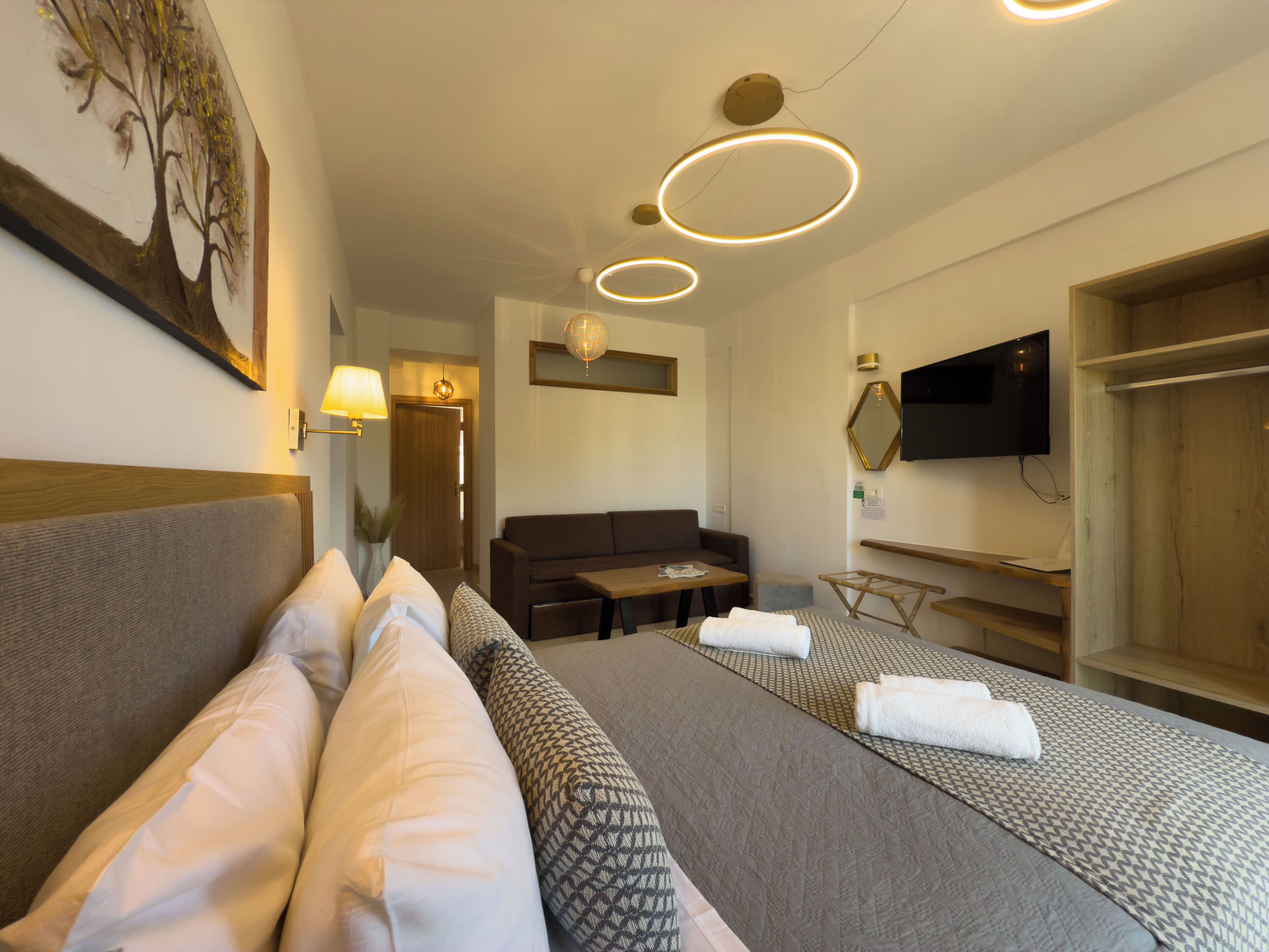 Ett hotellrum med en säng, en soffa, en tv och ett skrivbord.