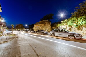 A street at night with parked cars and streetlights.