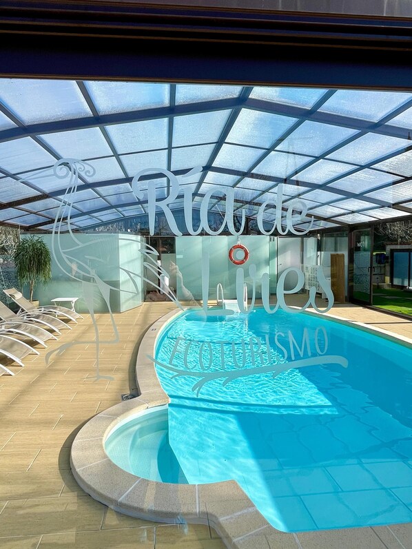 A swimming pool with a glass ceiling, lounge chairs, and a sign reading "Riad de Limes."