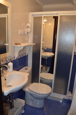 A bathroom with a white sink, a toilet, and a shower area.