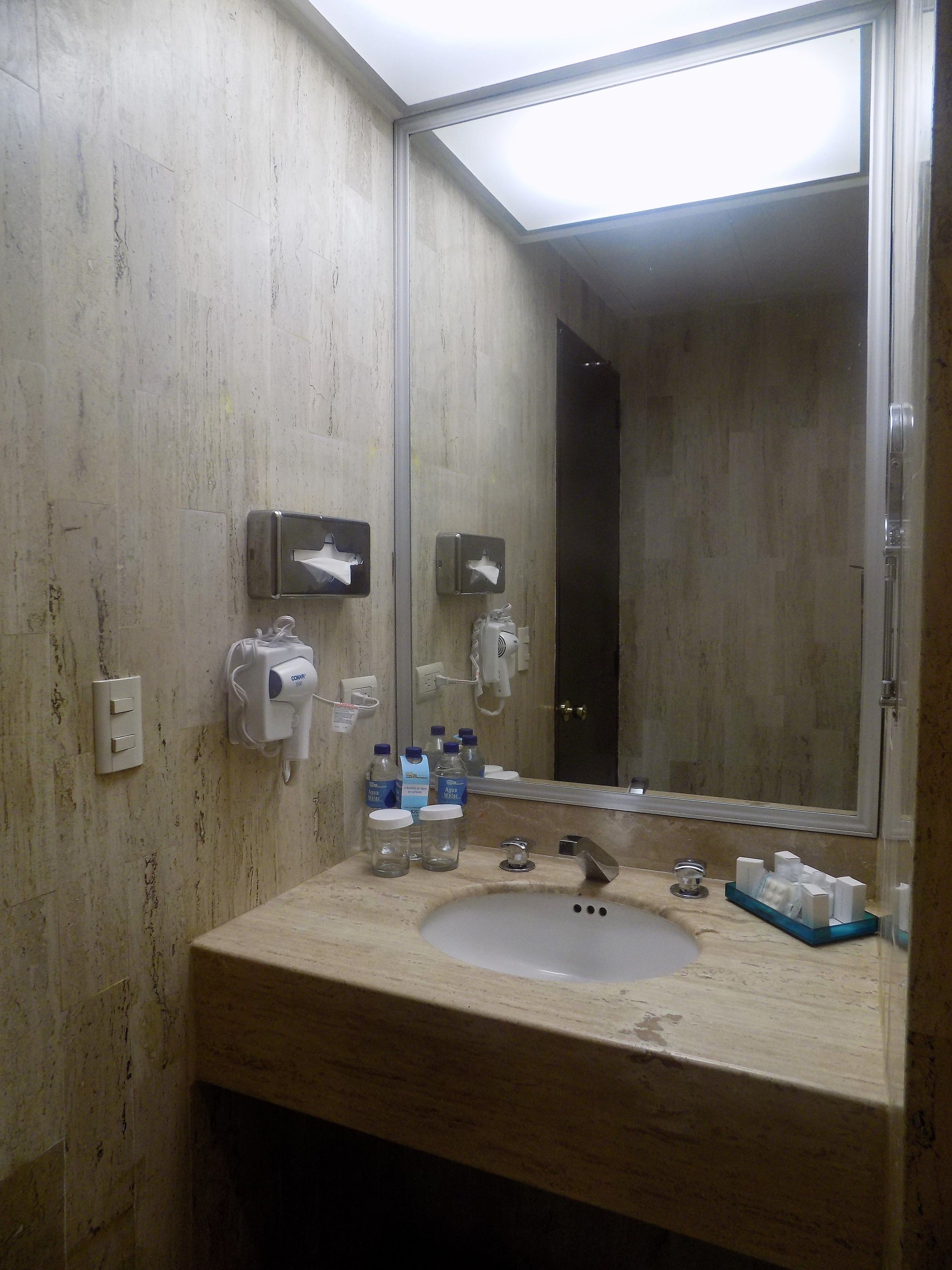 A bathroom with a sink, mirror, and hand dryer.