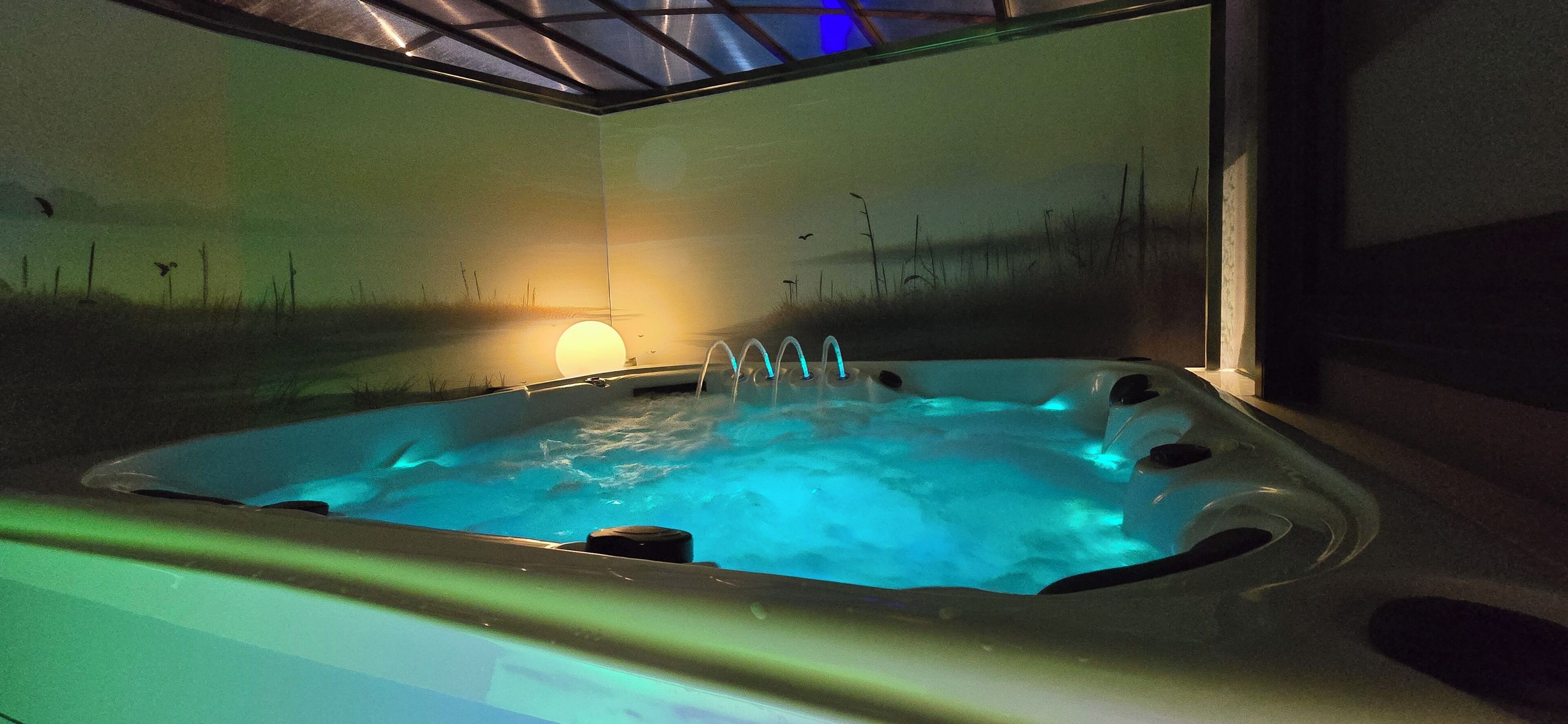 A hot tub with a view of a sunset over a grassy landscape.