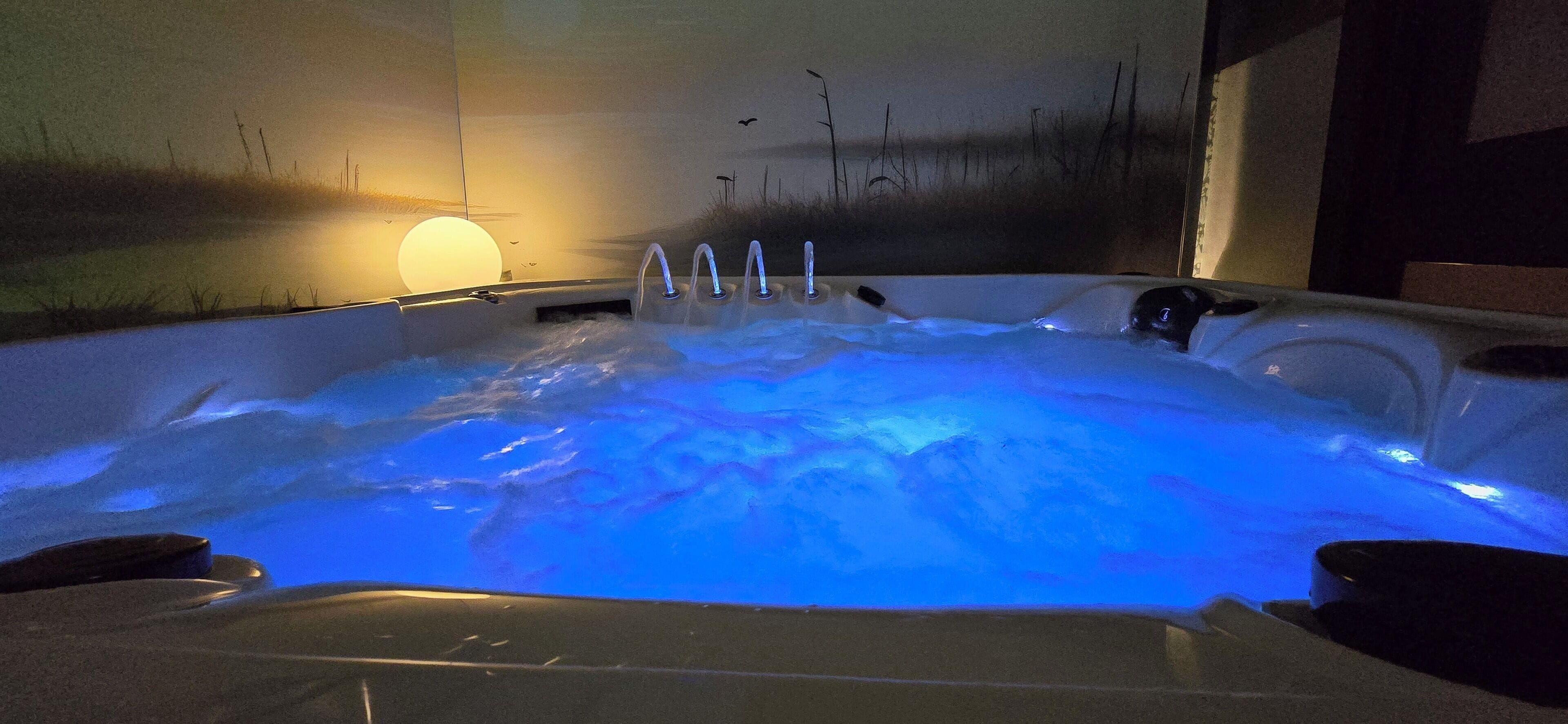 Una vasca idromassaggio con getti multipli, immersa in un ambiente interno tranquillo con un affresco e una luce soffusa.