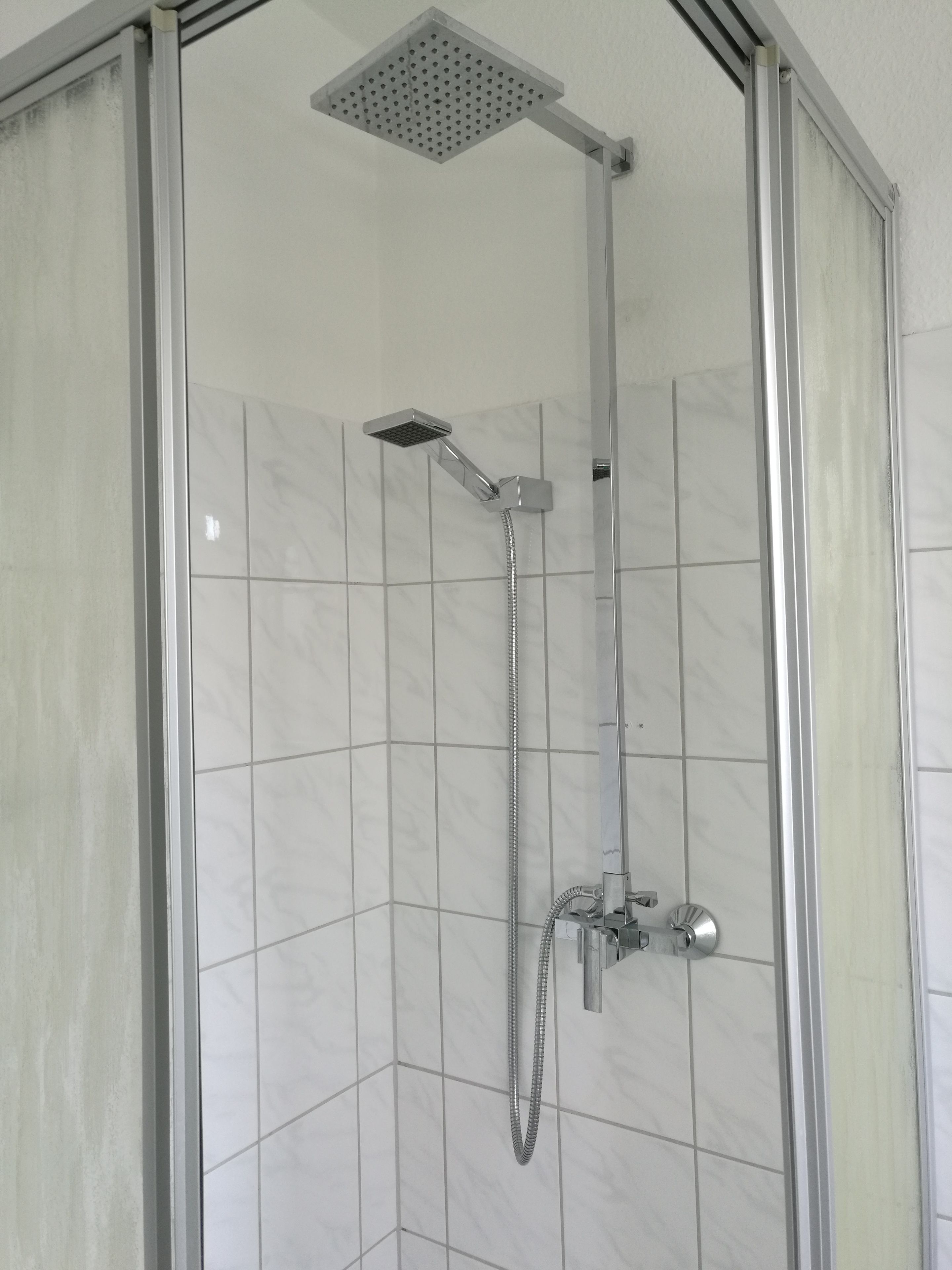 Ein Duschbereich mit Handbrause und Deckenbrause.