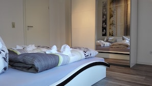 A modern bedroom with a large bed, a bedside table, and a mirror. - Hotel Villa Alice (Thale)