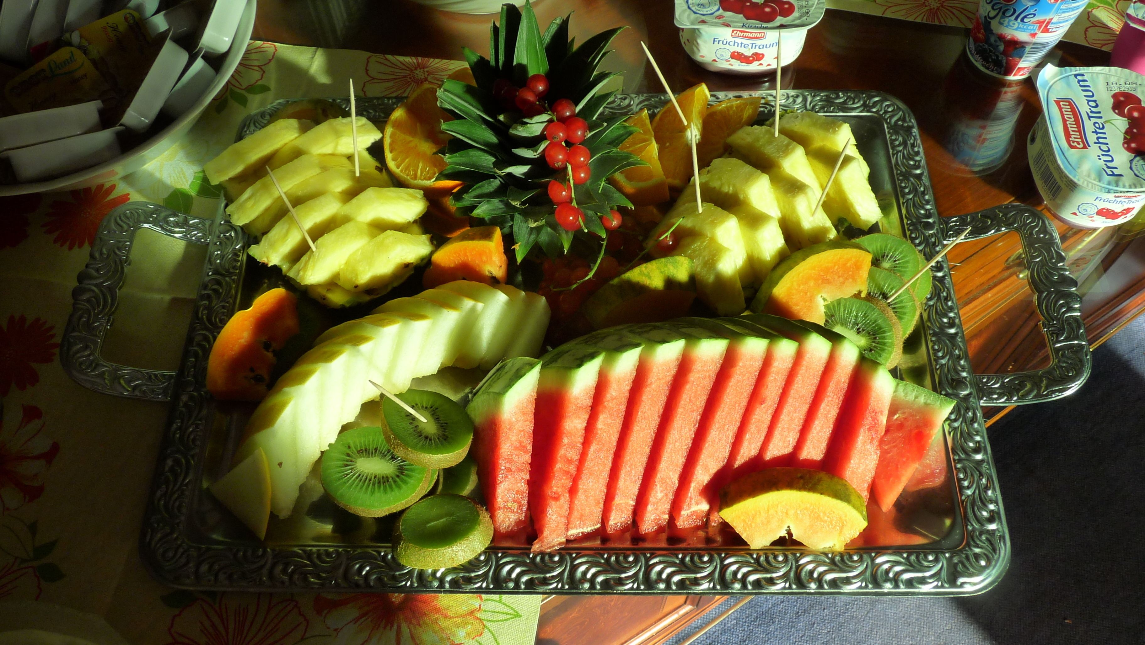 Una bandeja de frutas variadas y una planta decorativa.