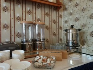 A breakfast buffet setup with tea dispensers, a coffee maker, and a bowl of tea bags. - Hotel Villa Alice (Thale)