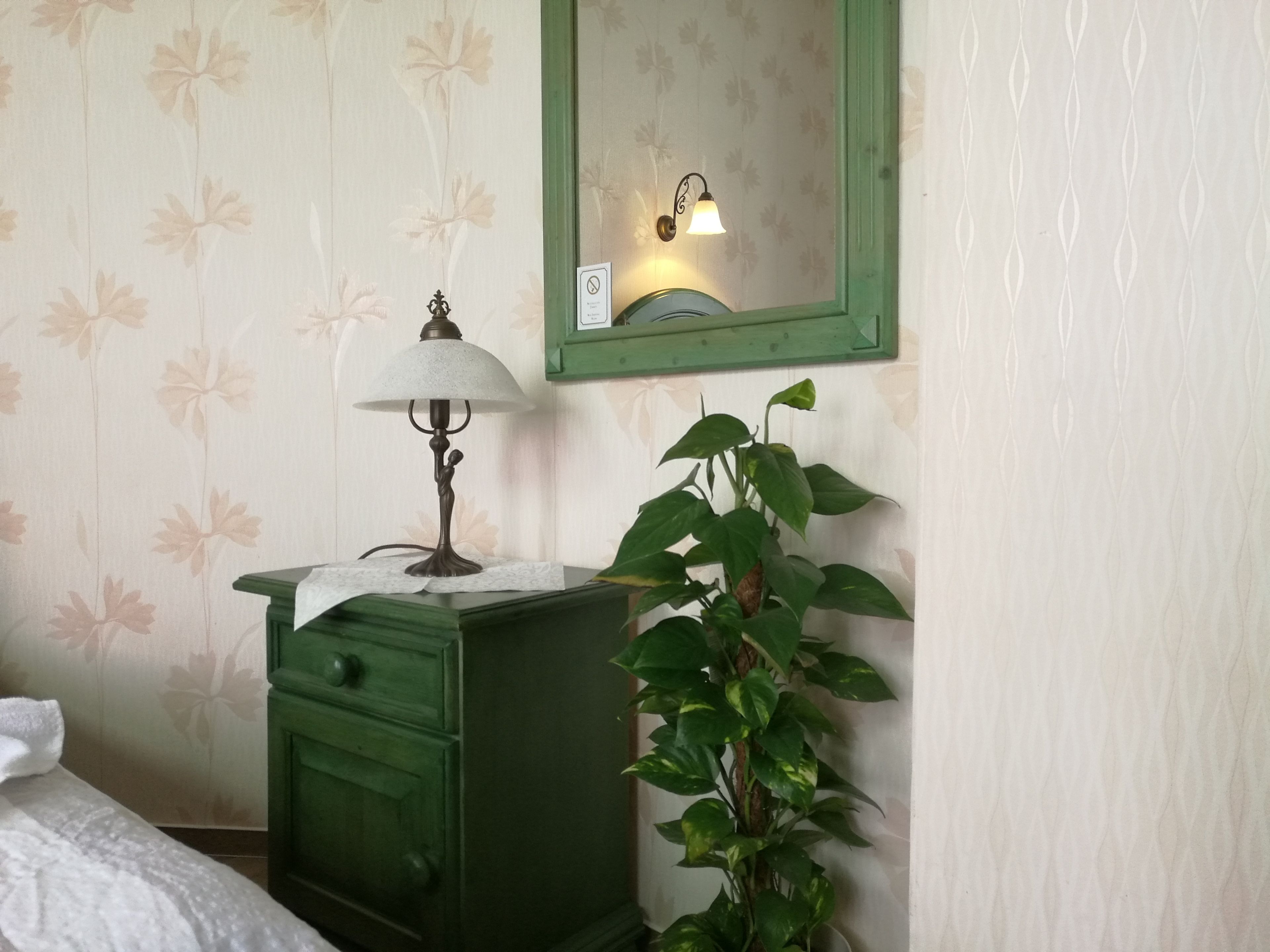 Una habitación con un aparador verde, una lámpara y una planta en maceta.