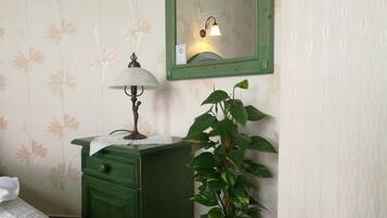 Una habitación con un aparador verde, una lámpara y una planta en maceta.