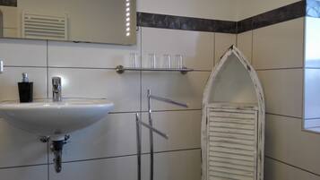 A bathroom with a white sink, a mirror, a towel rack, and a decorative shower enclosure.