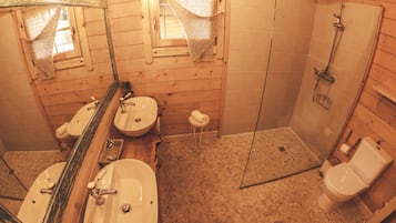 A wooden bathroom with two sinks, a toilet, and a shower.