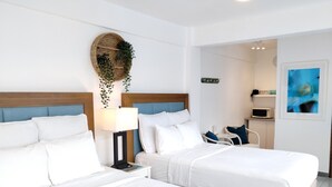 Ein Hotelzimmer mit zwei Betten, einem Nachttisch mit Lampe, einer kleinen Sitzecke mit Sessel und einer Mikrowelle auf einer Ablagefläche.