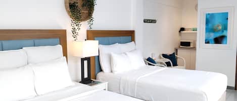 A hotel room with two beds, a bedside table, a lamp, a microwave, and a small seating area.