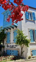 Un edificio de dos pisos con contraventanas azules, un balcón y un letrero que dice 'Boutique Hotel'.