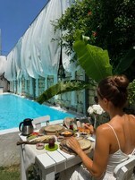 Mesa de comedor al aire libre, con una piscina al fondo.
