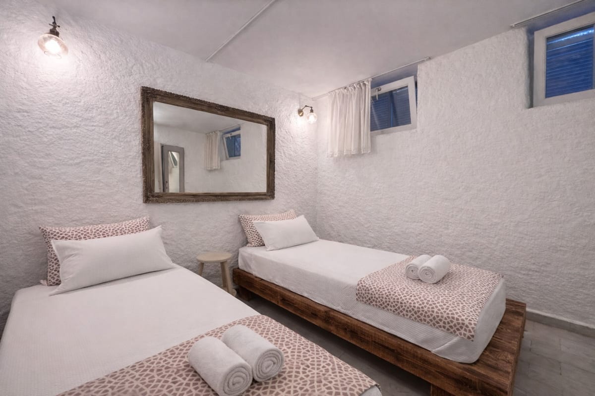 A room with two beds, a large mirror, a small table, and a window with curtains.