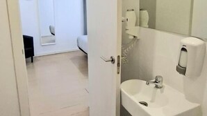 Ein Badezimmer mit Waschbecken, Spiegel und einer Tür zu einem Schlafzimmer.
