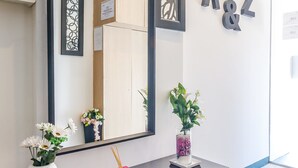 Ein Empfangsbereich mit einer dunklen Konsole, zwei Vasen mit Blumen, einem roten Räuchergefäß und einem großen Spiegel, der das Innere widerspiegelt.