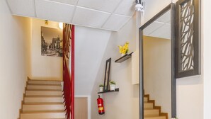 Eine Treppe mit roter Handlauf, ein Flur mit einem großen Spiegel und ein Feuerlöscher an der Wand.