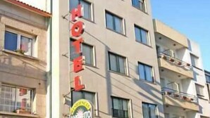 A hotel building with multiple floors, a prominent 'HOTEL' sign, and a 'SANITARY' sign indicating facilities. - Hotel Angelito (O Grove)