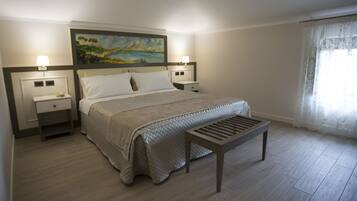 Une chambre à coucher bien rangée, avec un lit, des tables de chevet, un banc et un tableau accroché au mur.