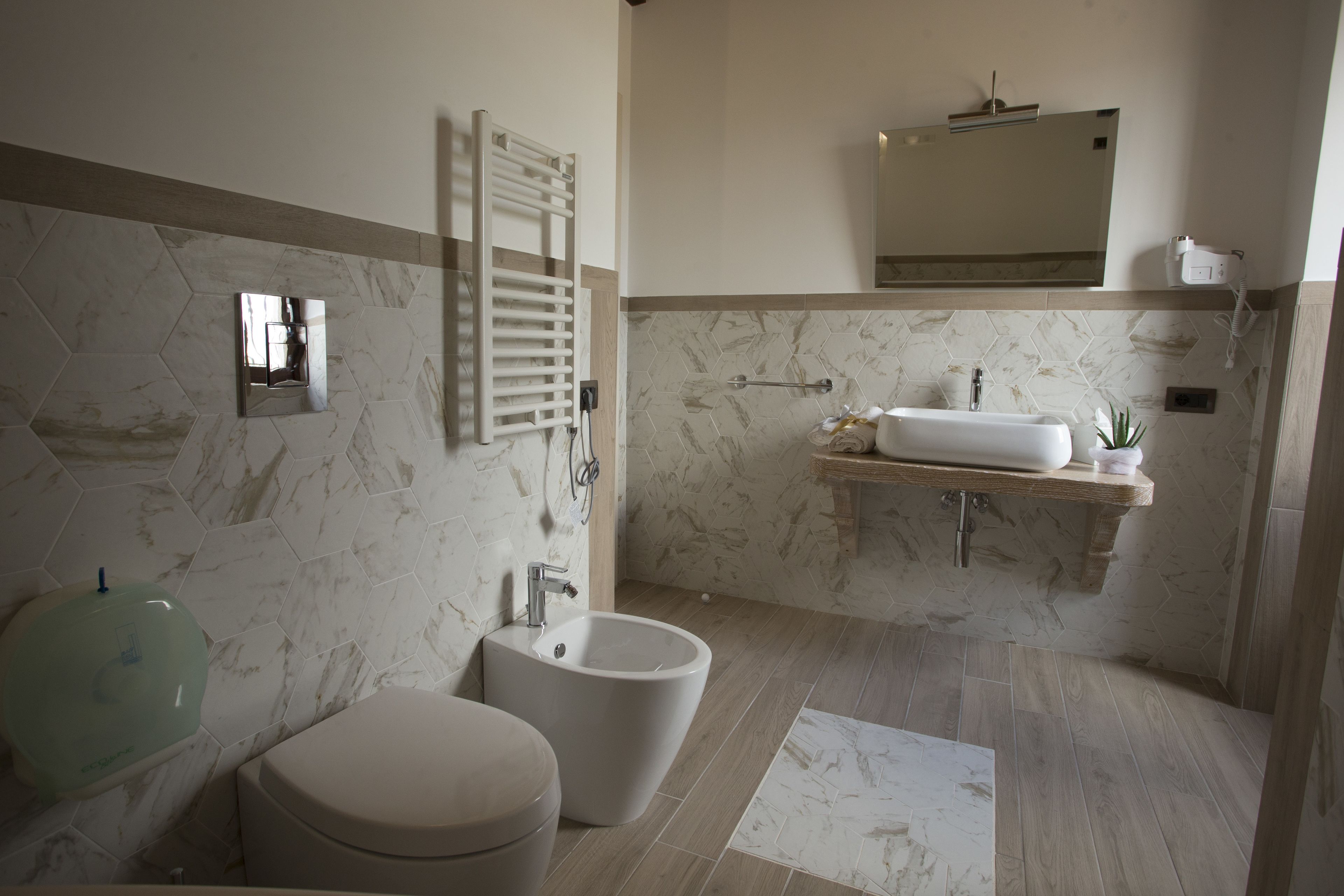 Une salle de bain moderne équipée d’un bidet, de toilettes et d’un meuble-lavabo avec un miroir.