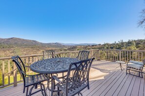 Una terrazza con un tavolo rotondo e sedie, affacciata su un paesaggio montuoso.