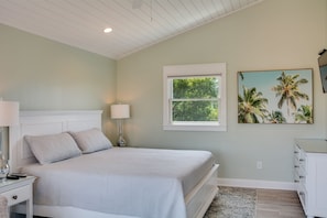Une chambre à coucher avec un lit, des tables de chevet, une lampe, une fenêtre, un tableau et une commode.