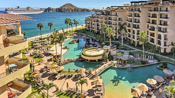 Un complexe hôtelier doté de plusieurs piscines, d’une plage et, au loin, d’un navire de croisière.