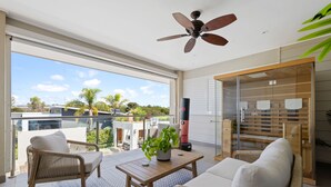 Ein geräumiger Balkon mit Korbmöbeln, einem Deckenventilator und Blick auf die Umgebung.