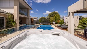 Ein modernes Haus mit Swimmingpool, Sitzgelegenheiten im Freien und Whirlpool.